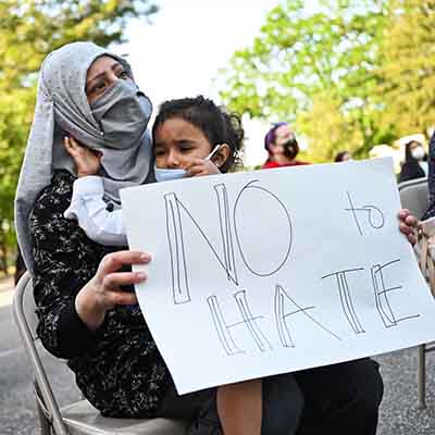 Person with child holds sign that reads No Hate